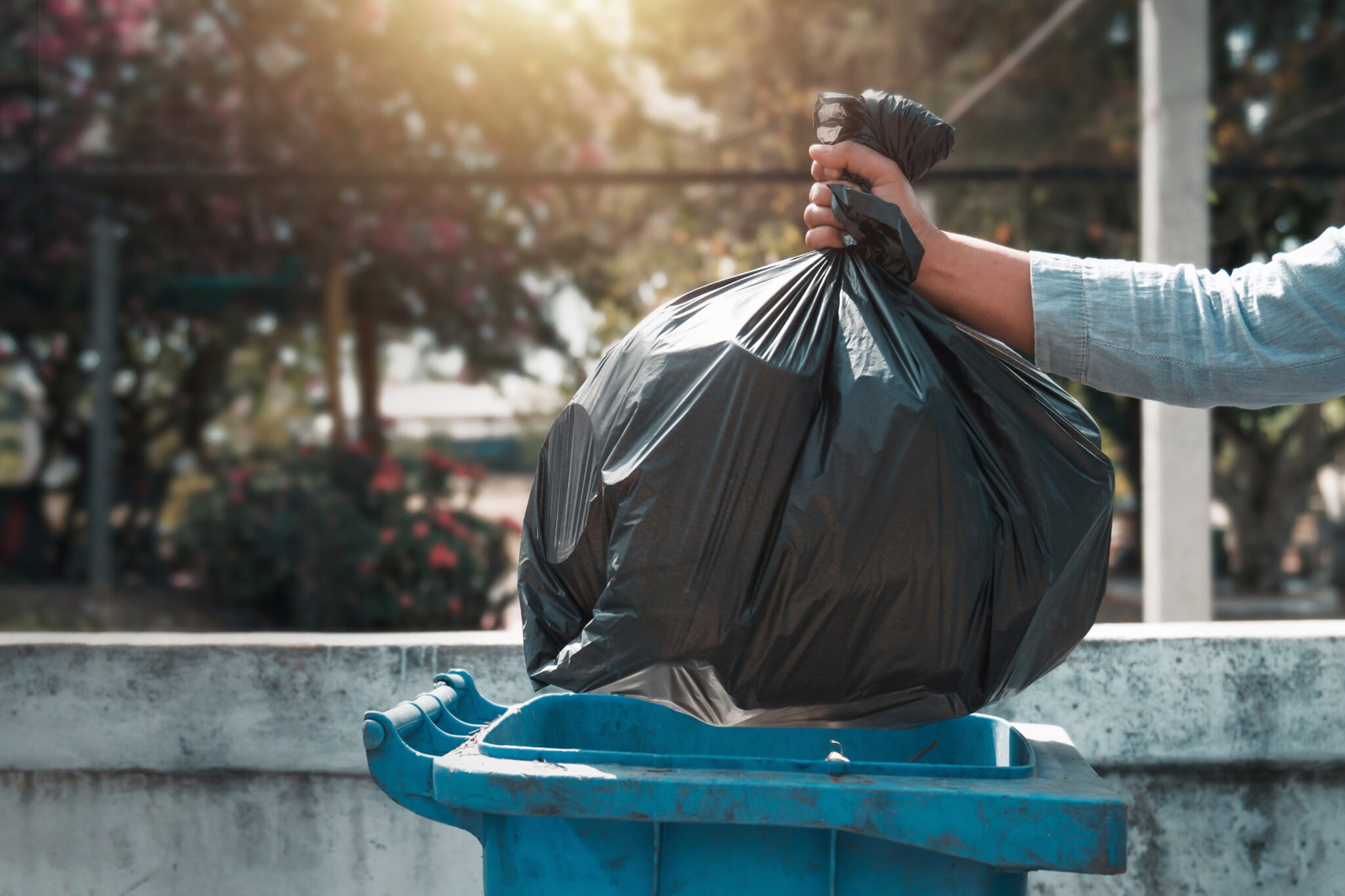 hand holding garbage black bag putting in to trash The City Of Kingsville